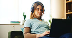 Laptop, headphones and woman on sofa with online course, research or education webinar in home. Elearning, relax and student girl on couch with computer, connection or music steaming in apartment