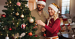 Christmas, help and tree with couple and decoration for bauble, gift giving and festive season. Xmas, holiday and celebration with man and woman in living room at home for tradition, noel and winter