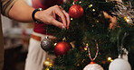 Ornaments, tree and decoration for Christmas, hand and tradition for festive, color and bright with lights. Creative, holiday and season of celebration, home and detail on ball,  sparkle and person