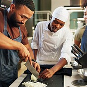 Cooking, course and chef teaching man in kitchen for knife skills ...