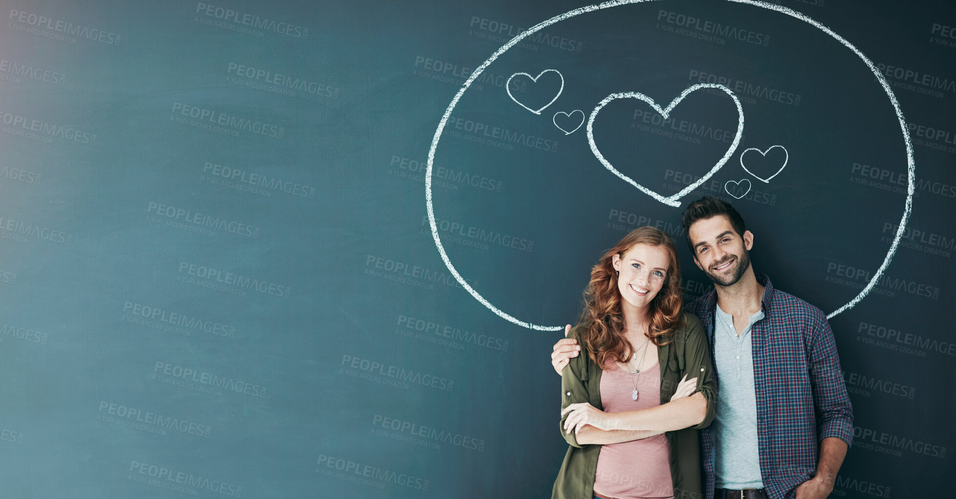 Buy stock photo Portrait of a young couple standing in front of a blackboard with a circle drawn around them