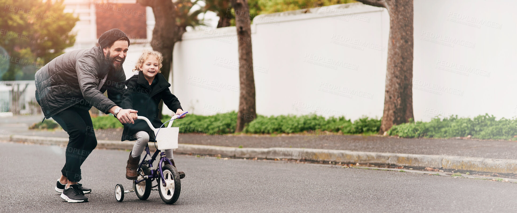 Buy stock photo Shot of a father teaching his little daughter how to ride a bicycle