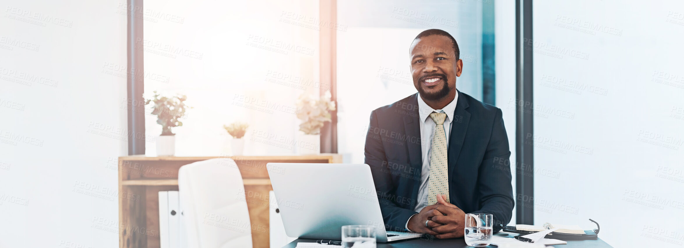 Buy stock photo Portrait, business and happy black man in office at table on laptop for corporate job in Kenya. Face, smile and African professional entrepreneur, employee and confident attorney in suit for work