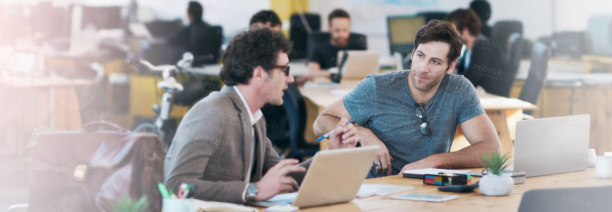 Buy stock photo Shot of business colleagues discussing matters with the help of wireless technology in their office