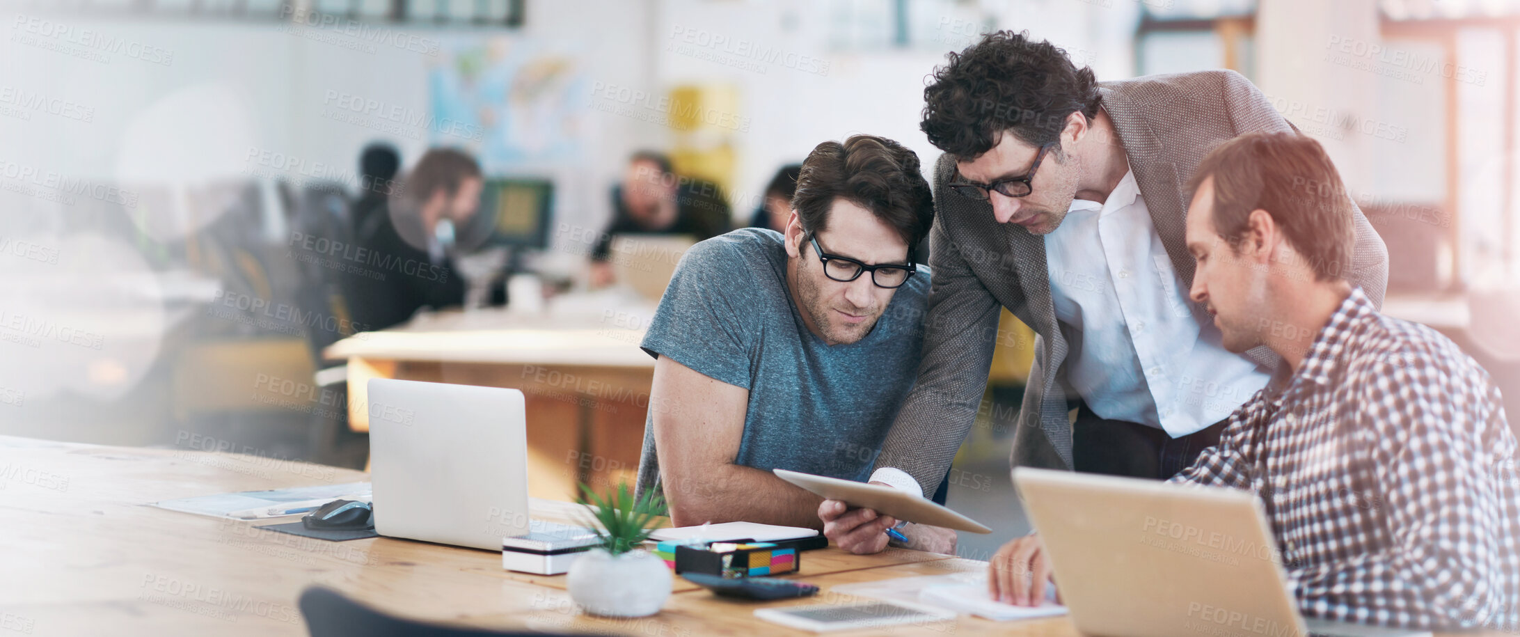 Buy stock photo Shot of business colleagues discussing matters with the help of wireless technology in their office