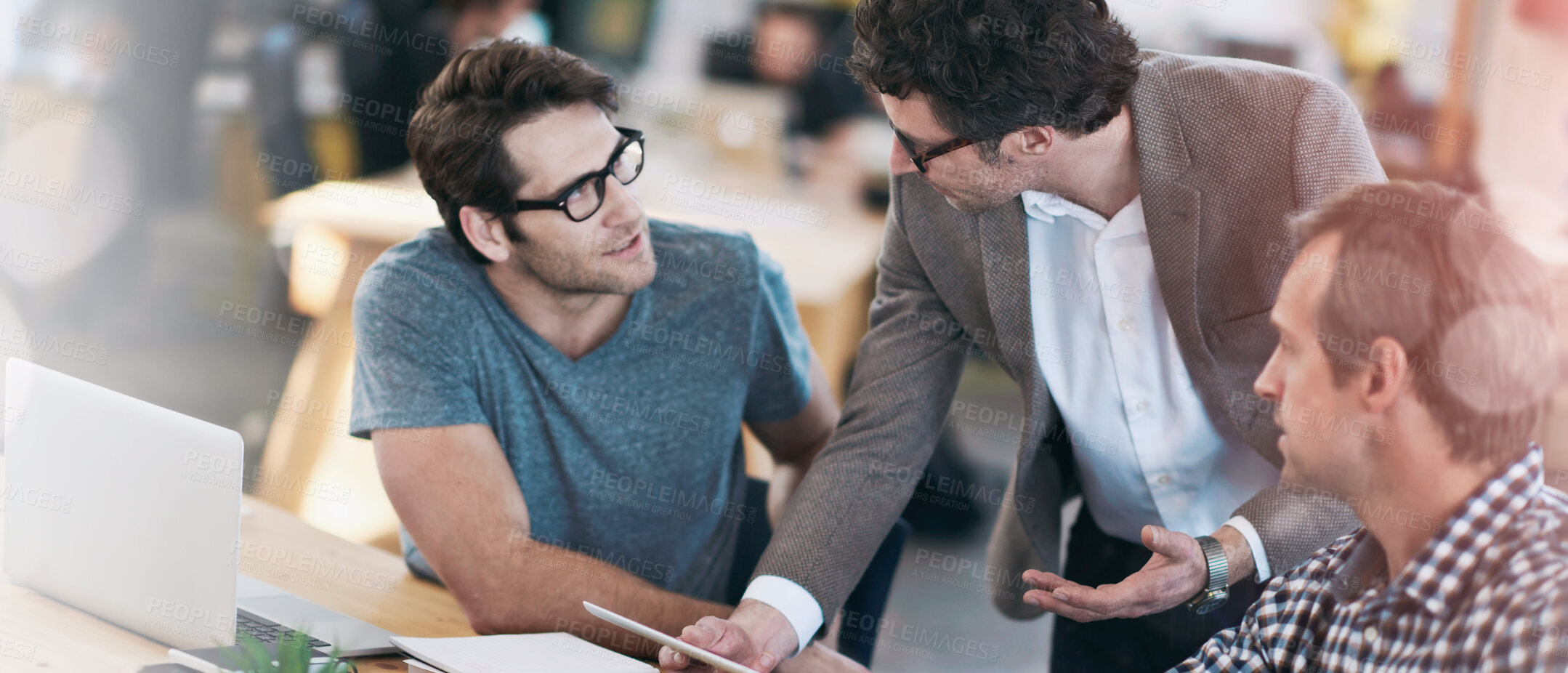 Buy stock photo Shot of business colleagues discussing matters with the help of wireless technology in their office