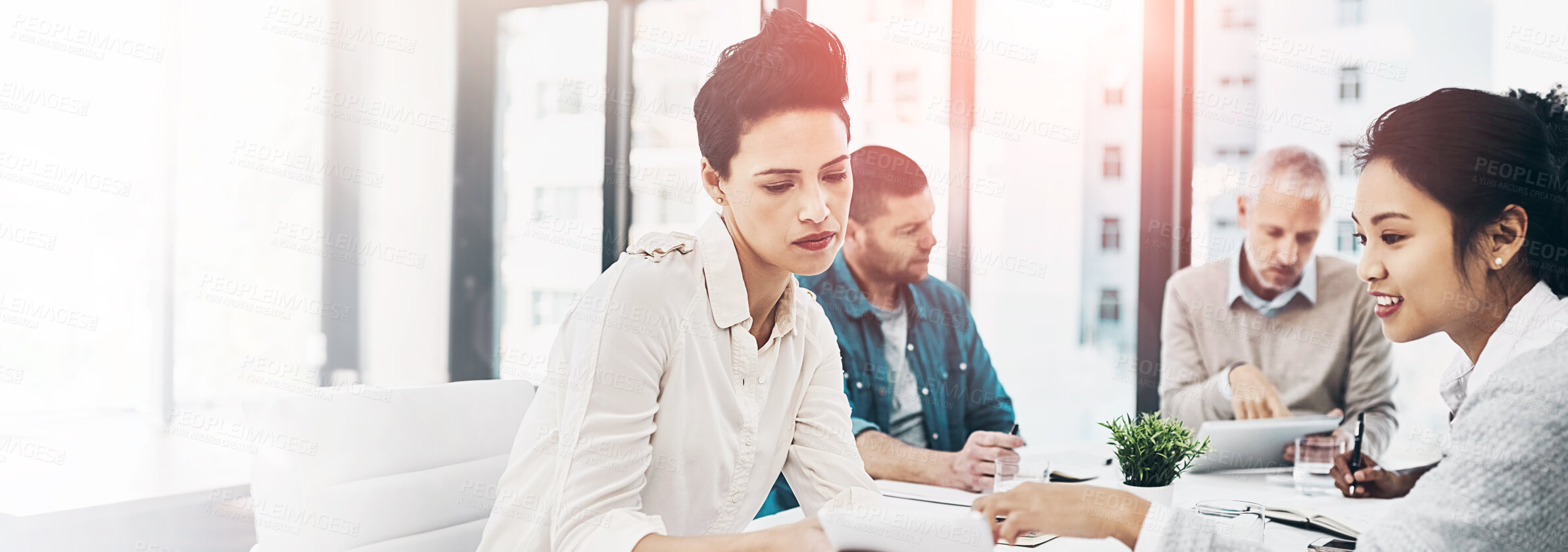 Buy stock photo Shot of two coworkers talking together over a digital tablet while sitting together in a meeting