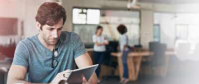 Buy stock photo Shot of a young man working on a digital tablet in an office