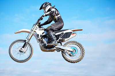 Buy stock photo Person, motorcycle and air jump in blue sky as professional in action, competition or fearless. Bike rider, off road transportation stunt or fast speed adventure at rally, extreme sport or challenge