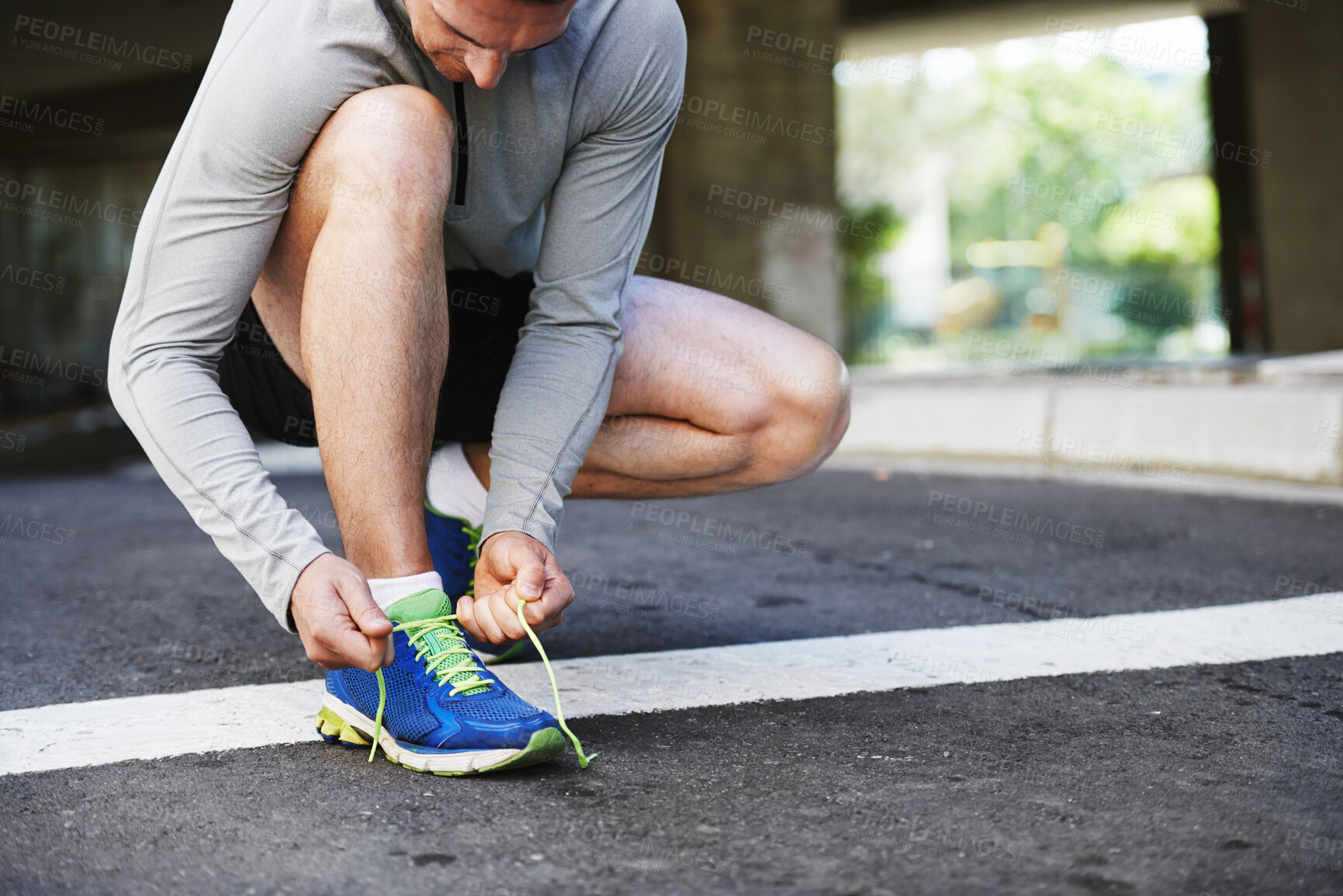 Buy stock photo Cropped shot of a young man tying his laces before a run