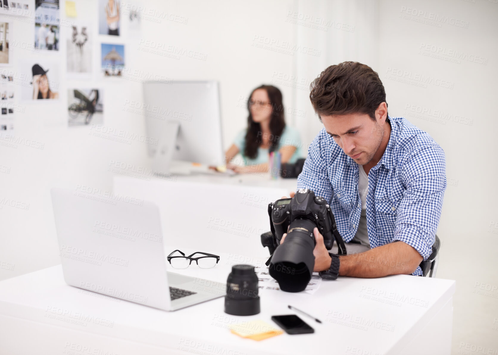 Buy stock photo Camera, office and photographer looking at photoshoot in a studio or workshop for production. Creative, photography and young artist with dslr equipment for picture inspection in modern workplace.