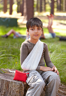 Buy stock photo Child, portrait and first aid for hurt arm with sling on bruise for medical treatment outdoors on tree trunk. Kid, emergency kit and bandage for muscle sprain, injury and camp accident in nature.