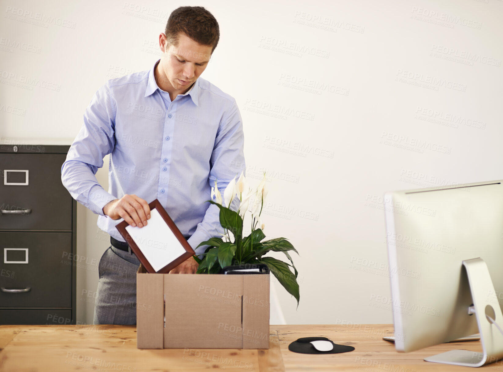 Buy stock photo Shot of a young businessman packing his belongings away