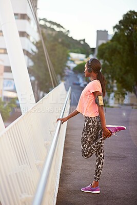 Buy stock photo Black woman, profile and stretching with headphones for fitness, workout preparation or exercise on bridge in city. African, female person or runner with leg for warm up or getting ready for training