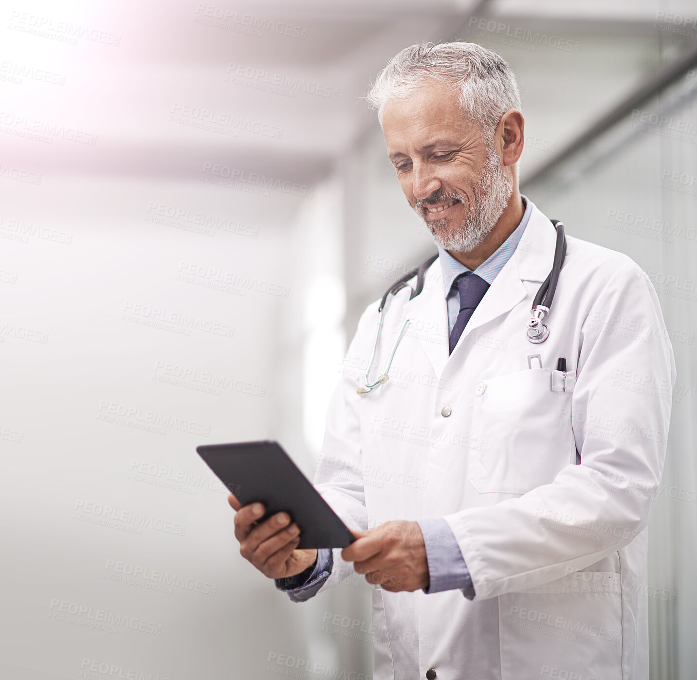 Buy stock photo Shot of a mature doctor using a digital tablet in a hospital