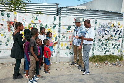 Buy stock photo Full length shot of volunteer workers addressing a group of children at a community outreach event