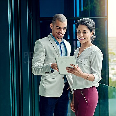 Buy stock photo Shot of two young coworkers using a digital tablet together at work