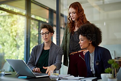 Buy stock photo Cropped shot of colleagues working together on a laptop in a modern office