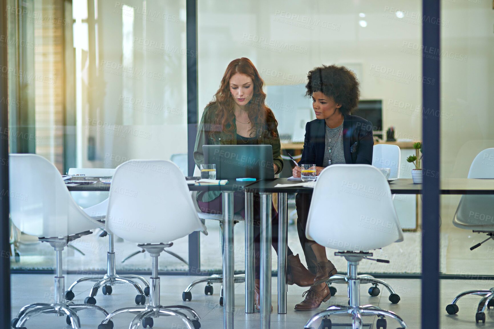 Buy stock photo Shot of colleagues working together on a laptop in a modern office