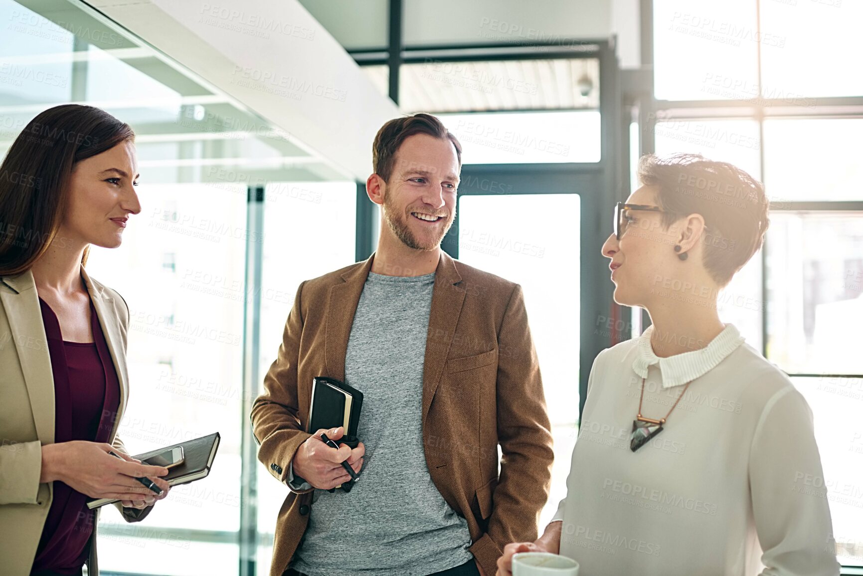 Buy stock photo Shot of a group of colleagues talking together in a large modern office