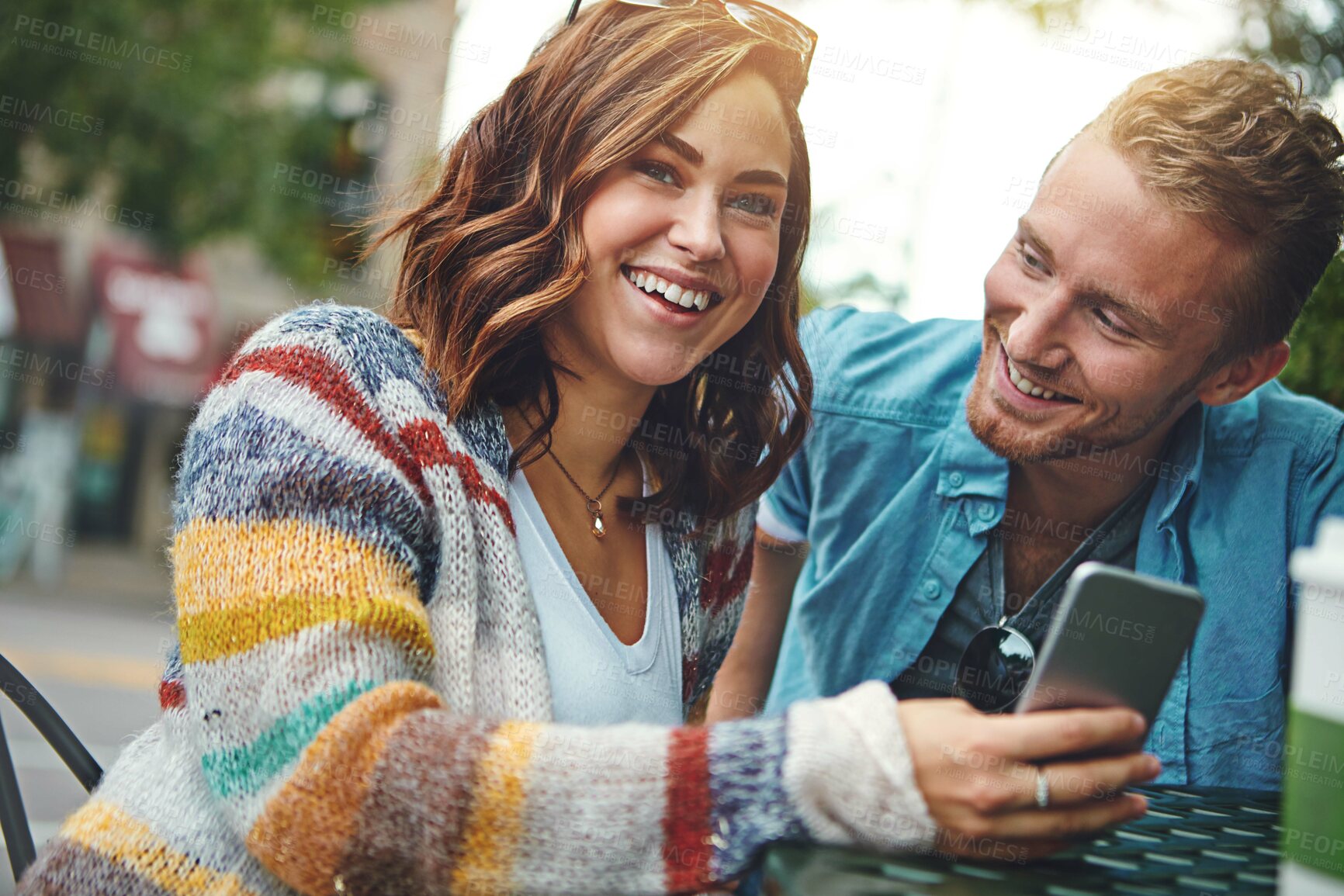 Buy stock photo Shot of a happy young couple using a smartphone together while spending the day downtown