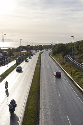 Buy stock photo Road, traffic and vehicles with cloudy sky in city for transport, commute or travel in an urban suburb. Street, path or route with natural scenery, land or asphalt for tourism, roadway or drive