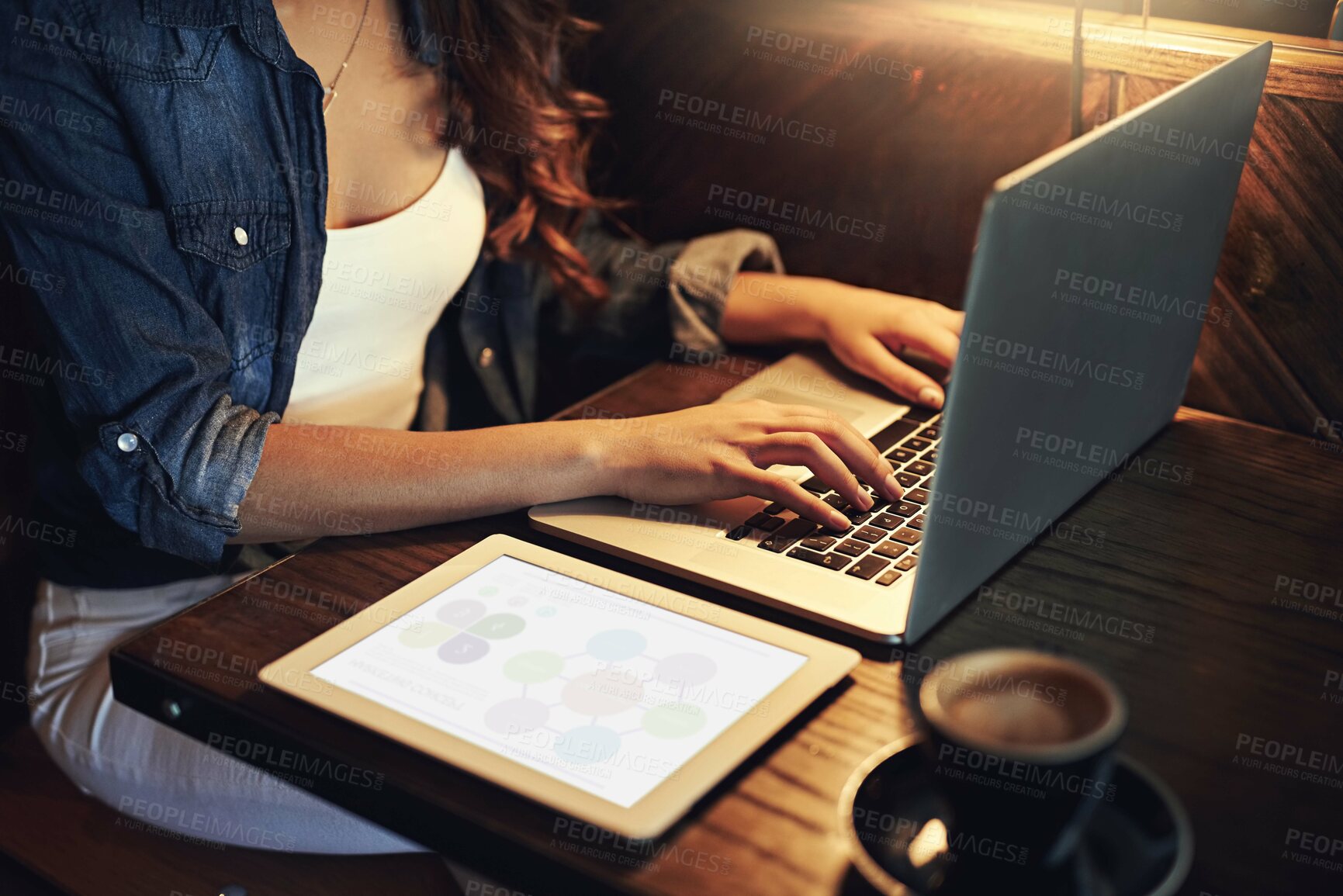 Buy stock photo Shot of an unidentifiable young woman using her laptop in a coffee shop