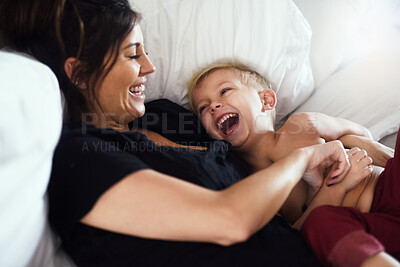 Buy stock photo Laughing, playing and mom with child in bedroom for bonding, love and fun relationship in morning. Family, home and mother with young boy on bed for tickle, joke and relaxing together on weekend