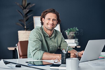 Buy stock photo Portrait of a handsome young businessman working on a laptop in his office