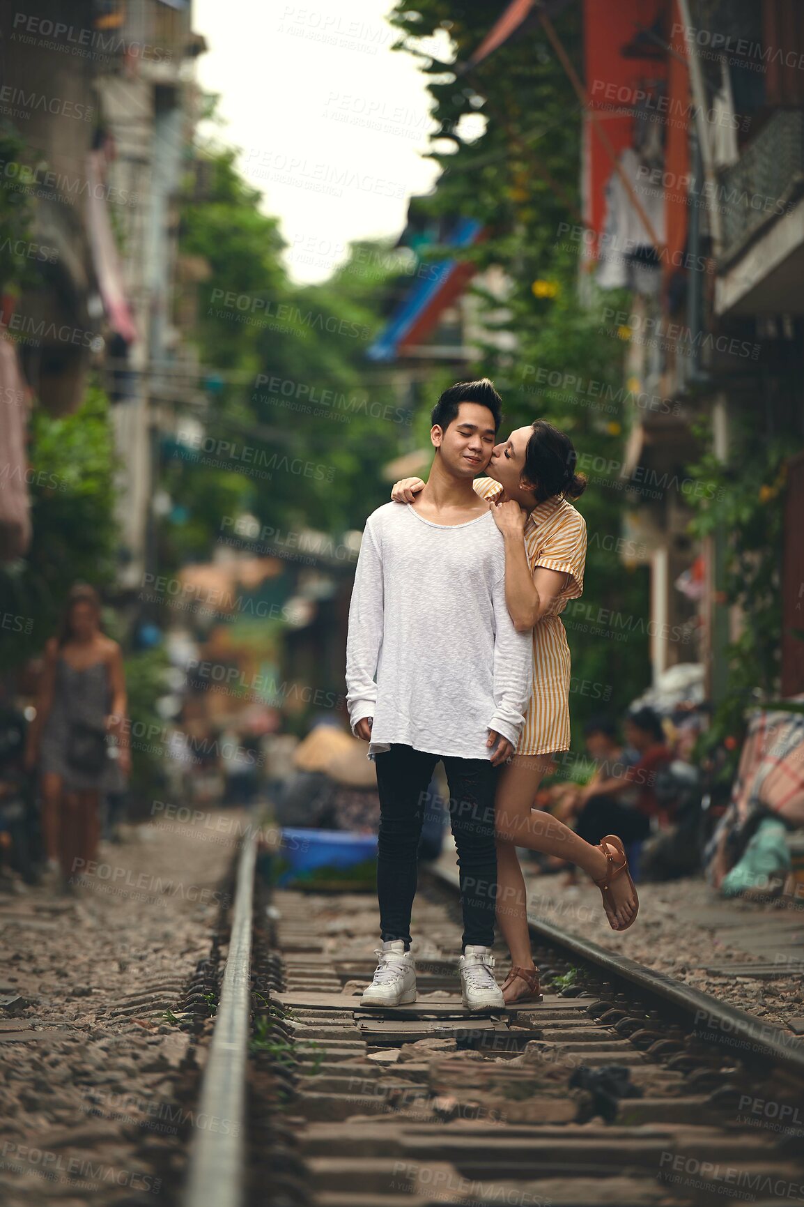 Buy stock photo Happy, kiss and couple on train tracks in Vietnam for holiday, vacation and tourist destination. Embrace, love and man and woman on railway for adventure, journey and travel for bonding in city