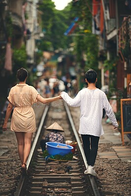 Buy stock photo Walking, holding hands and couple on train tracks in Vietnam for holiday, vacation and tourist destination. Travel, love and back of man and woman on railway for adventure, journey or bonding in city