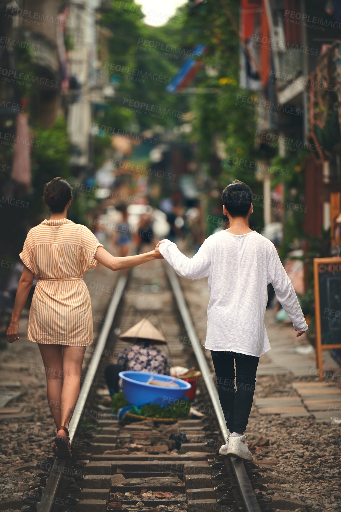 Buy stock photo Walking, holding hands and couple on train tracks in Vietnam for holiday, vacation and tourist destination. Travel, love and back of man and woman on railway for adventure, journey or bonding in city