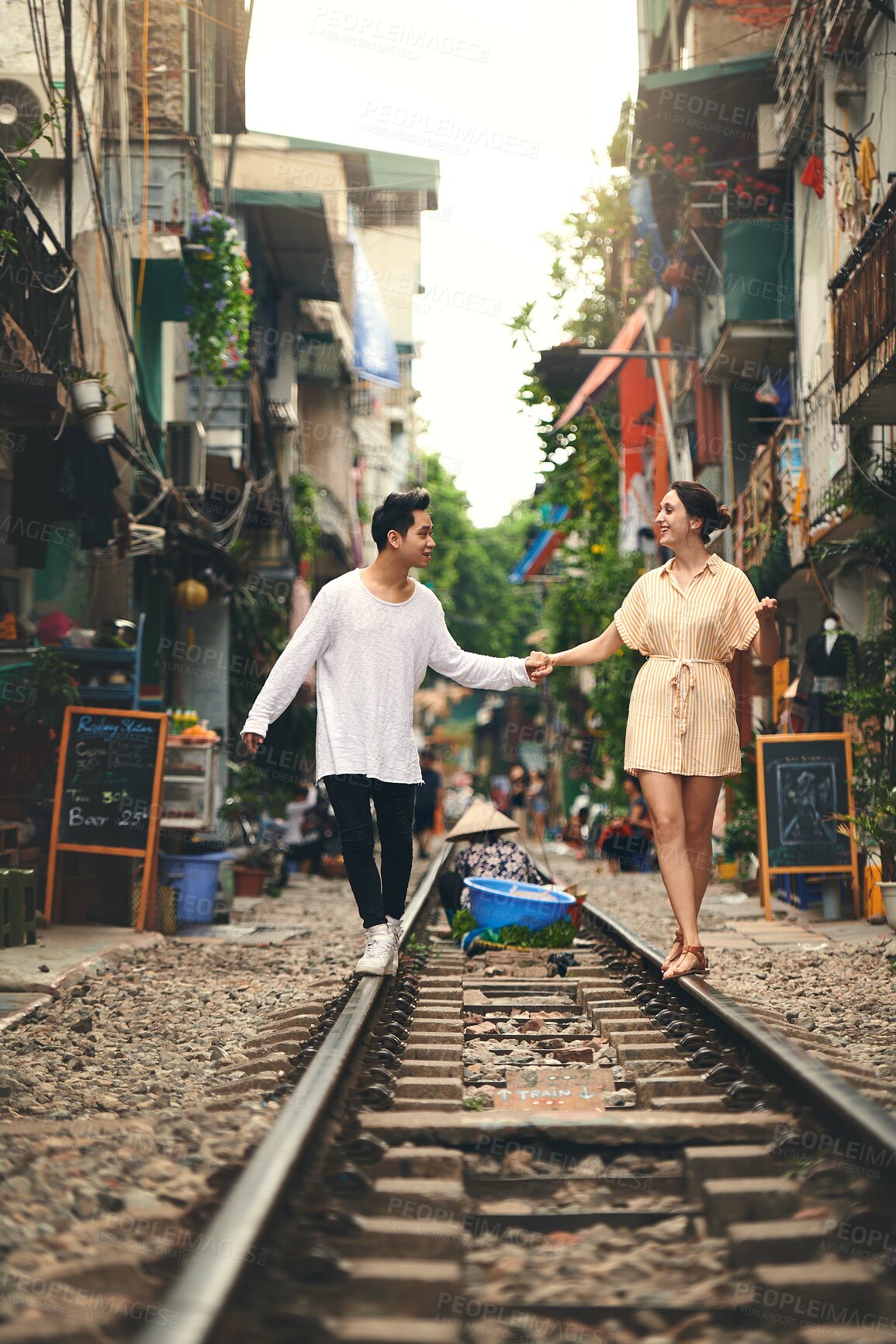 Buy stock photo Travel, walking and couple on train tracks in Vietnam for holiday, vacation and tourist destination. Holding hands, love and man and woman on railway for adventure, journey and bonding in urban city