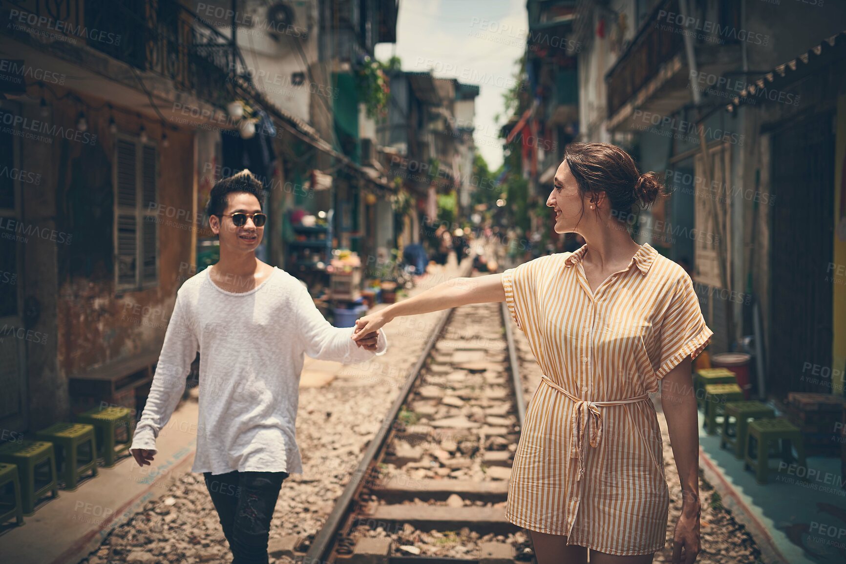 Buy stock photo Couple, happy and holding hands in city for love, romance gesture and healthy relationship with trust. Man, woman and travel on Vietnam railway for sweet moment, affection and date with commitment