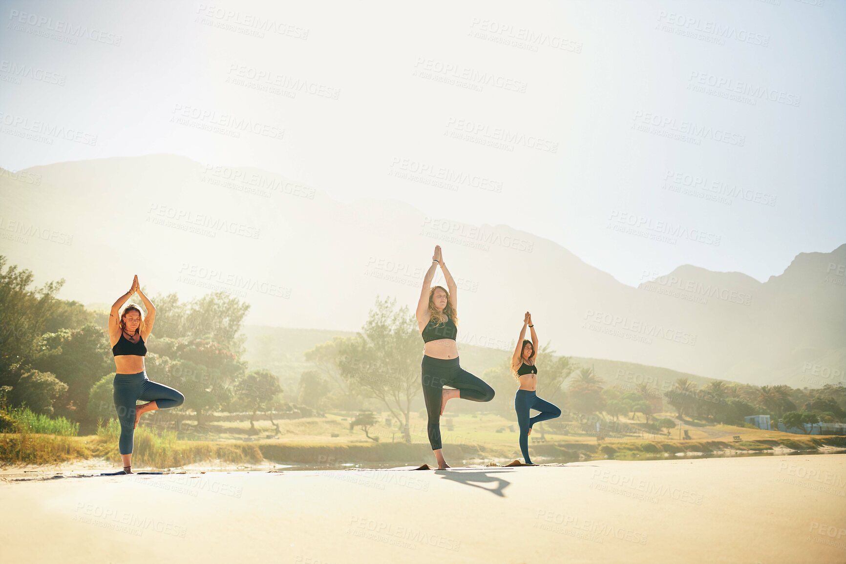 Buy stock photo Balance, yoga and women on beach in morning for wellness, peace and mindfulness in nature. Friends, pilates and people on sand for exercise, meditation and workout for health, stretching and mobility