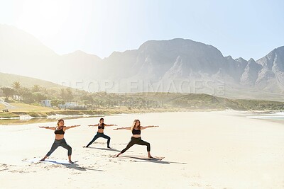 Buy stock photo Warrior pose, yoga and women by ocean for wellness, peace and mindfulness in nature. Morning, pilates and people on beach for exercise, meditation and workout for health, balance and stretching