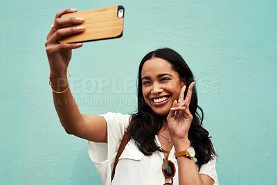 Buy stock photo Selfie, blue background and woman with peace sign in city for social media, online post and internet. Happy, weekend and person take photo for profile picture, travel blog and memory with emoji