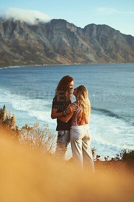 Buy stock photo Ocean, mountain and couple with love on holiday, travel vacation and bonding together with admiration. Outdoor, man and woman with hug for anniversary, connection or adventure with affection by flare