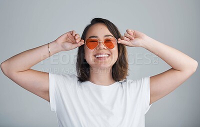 Buy stock photo Studio, asian woman and portrait with sunglasses for fashion, cool and holiday spirit with smile. Female person, model and happy with shades for stylish, heart accessory or tattoo by white background