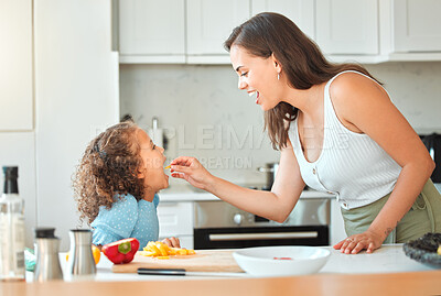 Buy stock photo Woman, child and feeding with smile, help and guidance for cooking and support in kitchen. Mother, girl and learning to cut vegetables for dinner, meal and healthy salad diet with fun bonding at home