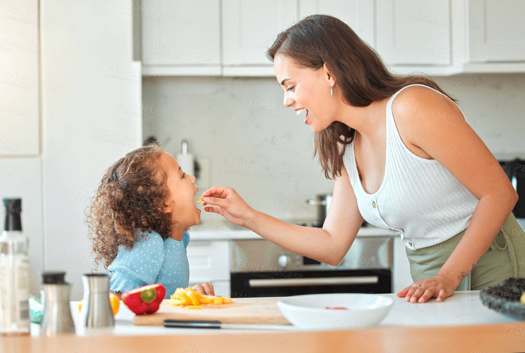 Buy stock photo Woman, child and feeding with smile, help and guidance for cooking and support in kitchen. Mother, girl and learning to cut vegetables for dinner, meal and healthy salad diet with fun bonding at home