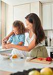 Happy mother teaching little daughter to cook in kitchen at home. Little girl adding seasoning pepper grinder to a bowl while making a salad with mom