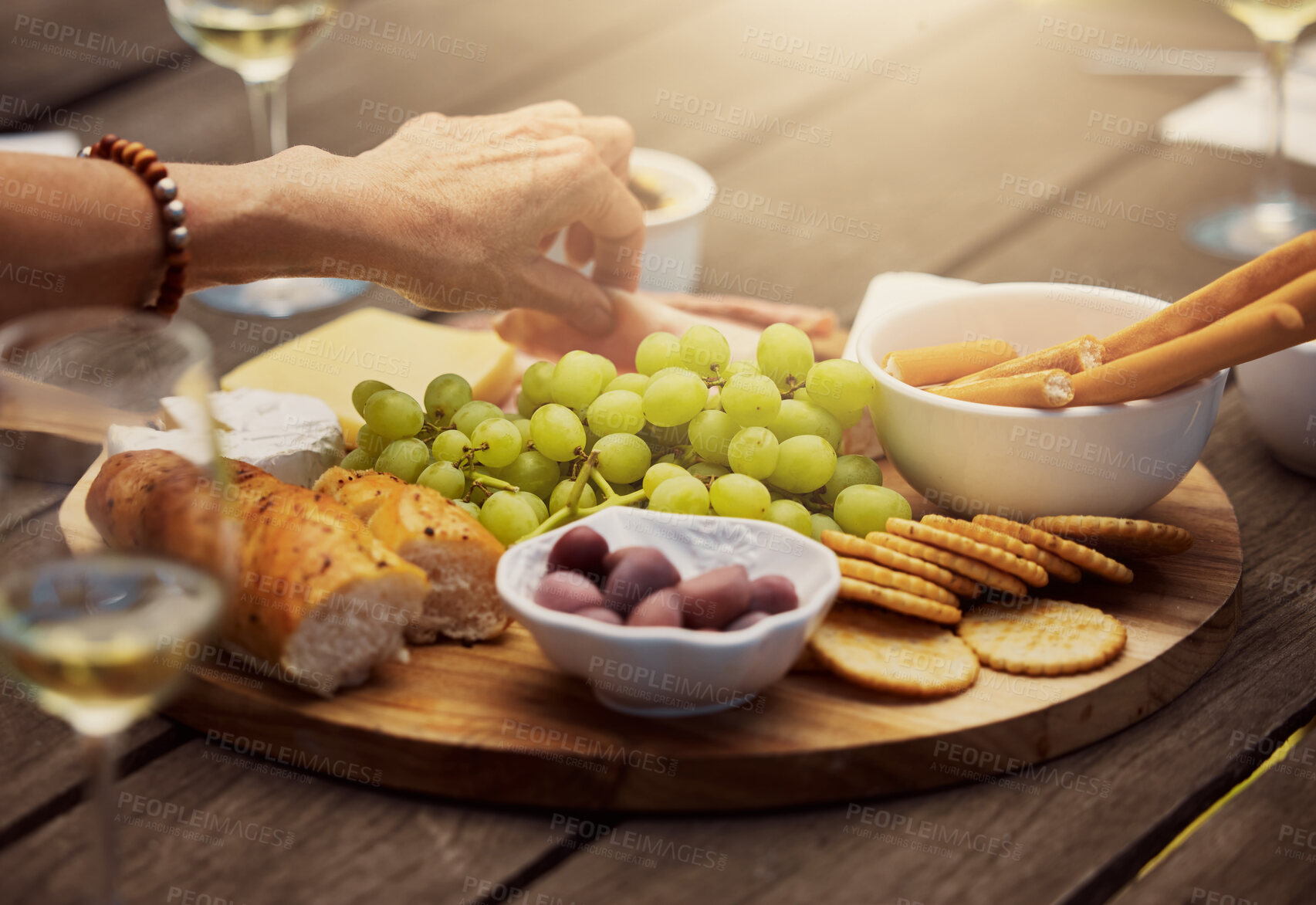 Buy stock photo Wine, cheese  and hands of woman at brunch buffet, celebration and picnic food in backyard. Bread, meat and fruit for charcuterie board on table at outdoor garden party for thanksgiving with drinks