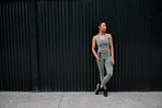 One young african american female athlete skipping using jump rope while exercising outside in the city. Beautiful and dedicated mixed race sportswoman working out alone against an urban background