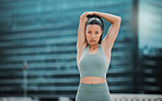 Portrait of a young hispanic female athlete looking serious while stretching before exercising outside in the city. Young woman warming up her muscles against a urban background. Stretching is most important