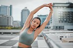 Portrait of a young mixed race female athlete looking serious while stretching her arms before her run in the city. Young woman warming up her muscles while during exercise against a urban background