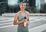 Happy young mixed race fit female athlete smiling while taking a break holding water bottle and working out in the city. Exercise is good for your health and wellbeing