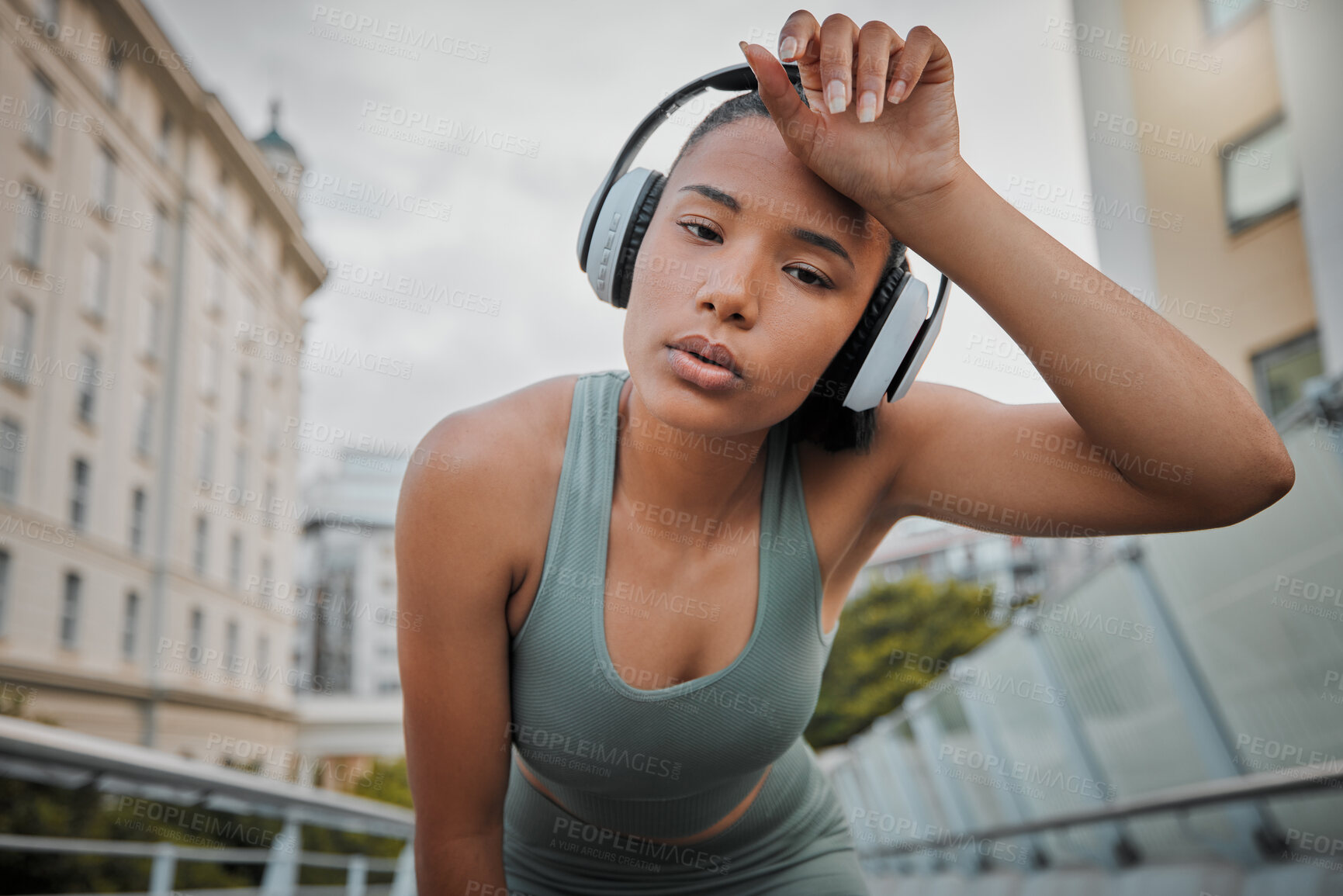 Buy stock photo Woman, portrait and tired athlete in city, wipe sweat and outdoor for streaming music in training. Female person, exhausted runner and wet head in town, morning fatigue and headphones for sound