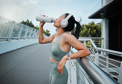 Buy stock photo Woman, headphones and drinking water outdoor for fitness, exercise and health with bottle and workout. Athlete, music and challenge in city for training, streaming and drink with healthy cardio run