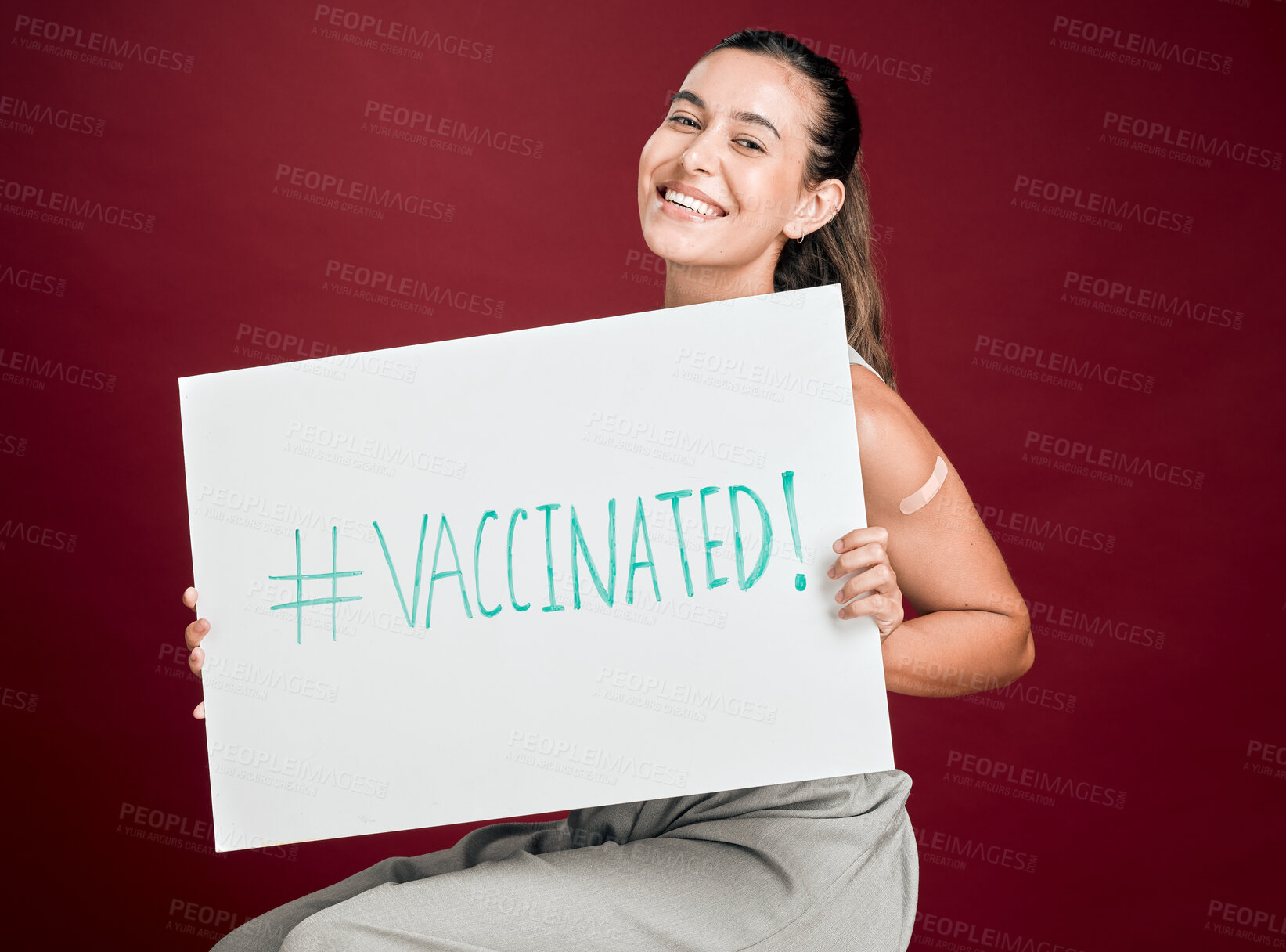 Buy stock photo Portrait, poster and vaccine with woman in studio isolated on red background for healthcare or medical. Hashtag, social media and smile of patient holding sign for covid awareness, cure or prevention